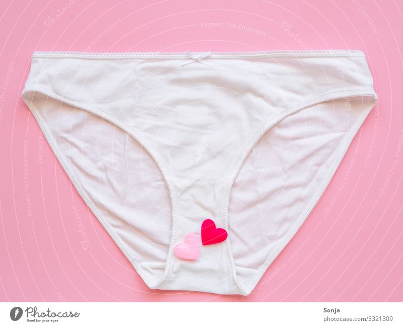 Weiße Frauenunterhose mit Herzen auf einem rosa Hintergrund, Draufsicht, Liebe Lifestyle Gesundheit Wohlgefühl Unterwäsche Unterhose Zeichen außergewöhnlich