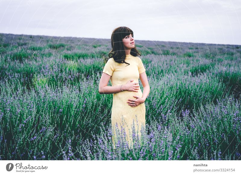 Liebenswerte junge Frau im ersten Monat der Schwangerschaft schwanger brünett Lavendel Blumen Frühling Wochen ein Monat zwei beginnend mit geblümt Feld Natur