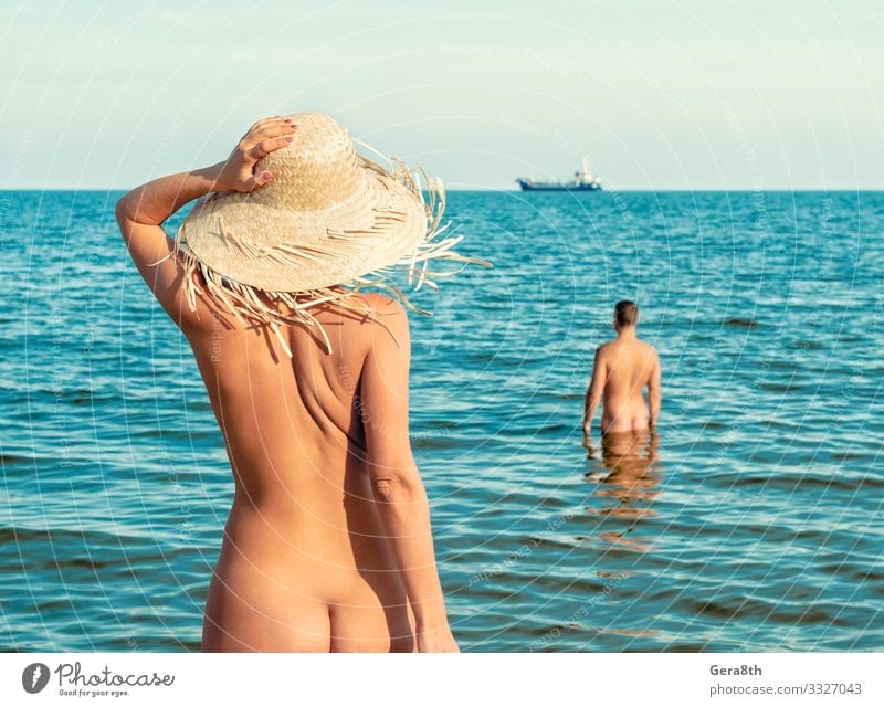 nacktes Mädchen mit Strohhut am Strand und ein nackter Mann steht im Wasser Haut Ferien & Urlaub & Reisen Sommer Meer Insel Wellen Frau Erwachsene Paar Hand