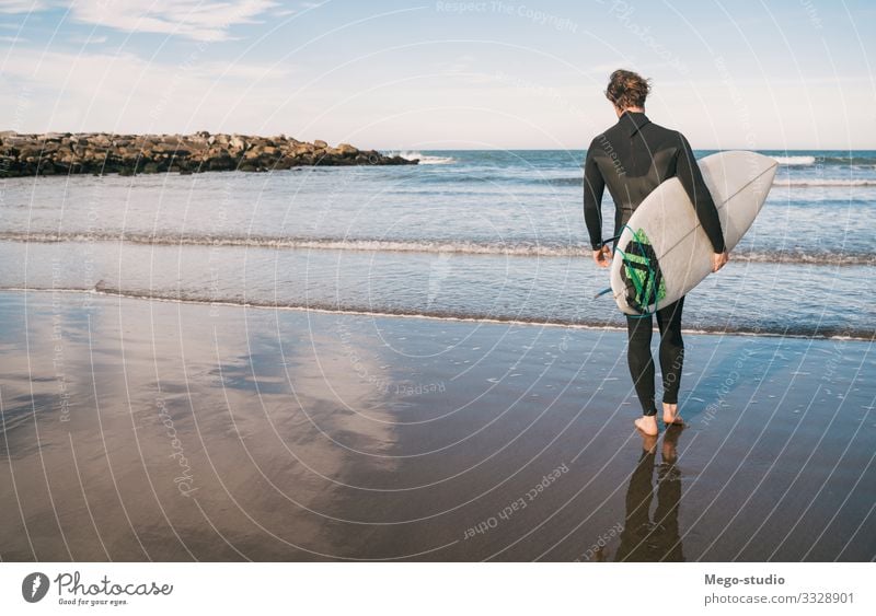 Surfer, der mit seinem Surfbrett ins Wasser geht. Lifestyle Freude Erholung Abenteuer Strand Meer Wellen Sport Wassersport Mensch maskulin Mann Erwachsene 1