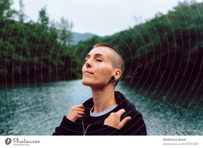 Unkonventionelle Frau genießt Regen in der Nähe eines natürlichen Teiches Natur Freiheit informell sinnlich provokant Kurze Haare Piercing lässig jung Skinhead