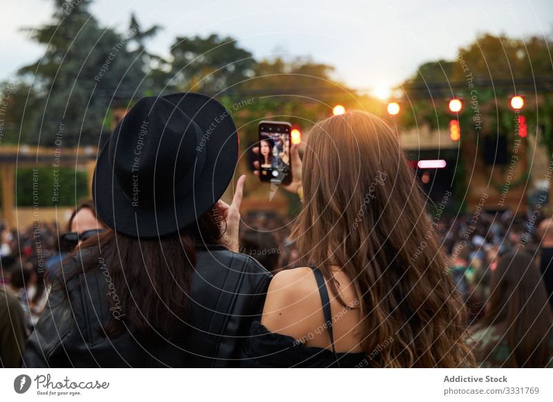 Langhaarige Frauen, die sich am sonnigen Tag in einer Gruppe von Menschen auf einem Smartphone selbstständig machen Freund Selfie Foto Stadtfest Feier