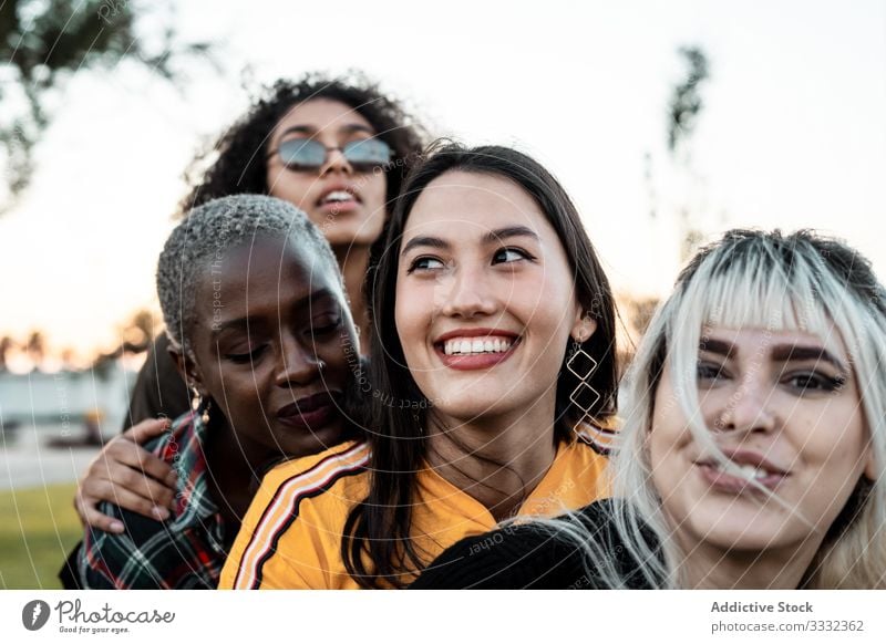 Diverse Gruppe von lächelnden Frauen, die sich auf dem Rasen umarmen Freund umarmend Menschengruppe Lächeln Lachen Kuscheln lässig Spaß Zusammensein jung