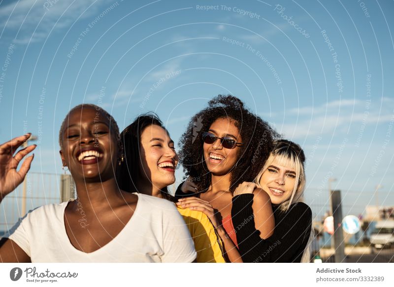 Zuversichtliche junge multiethnische Freundinnen, die sich auf der Straße vergnügen genießen Zeitvertreib Frau Spaß Sitzung Zusammensein Lifestyle Freizeit