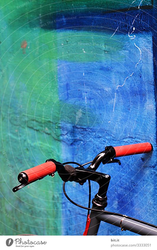 Fahrradlenker vom Rad, mit roten Griffen aus Gummi, steht geparkt, vor blauer, knalliger Wand, bei Pause der Fahhradtour, in der Stadt. Freizeit & Hobby Sport
