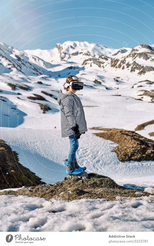 Aufgeregter Junge mit VR-Headset amüsiert sich in verschneiten Bergen erkunden Berge u. Gebirge Schnee Winter aufgeregt Resort Kind Oberbekleidung Schutzbrille