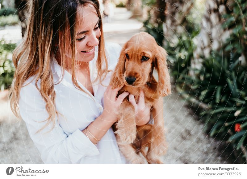 junge Frau und ihr süßer Cockerspaniel-Welpe im Freien in einem Park Hund Haustier Sonnenstrahlen Außenaufnahme Liebe Umarmen Lächeln Rückansicht Küssen züchten