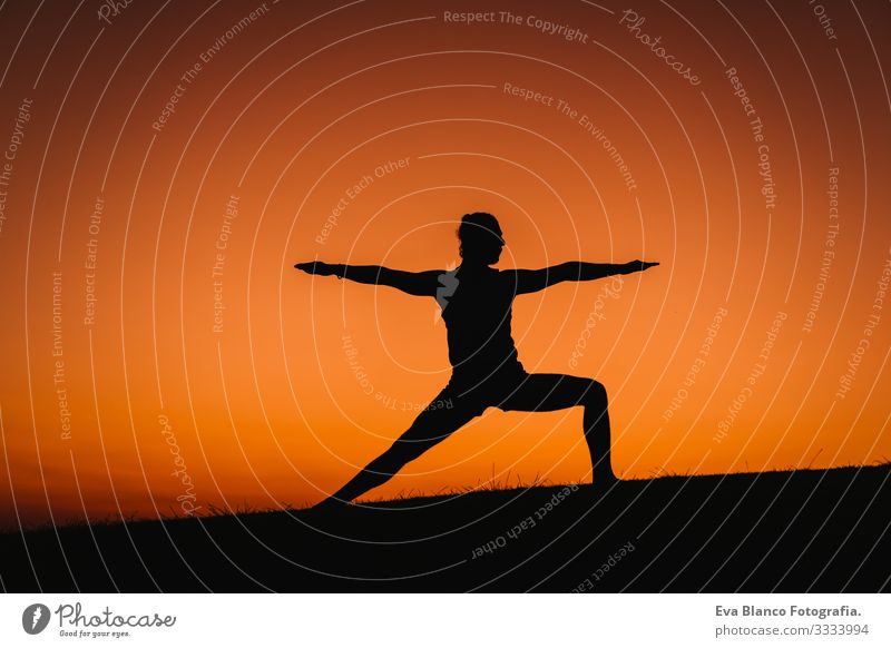 Silhouette eines jungen Mannes in einem Park, der Yoga-Sport betreibt. oranger Himmelshintergrund. gesunde Lebensweise. Gegenlicht Konzentration Posten Mensch