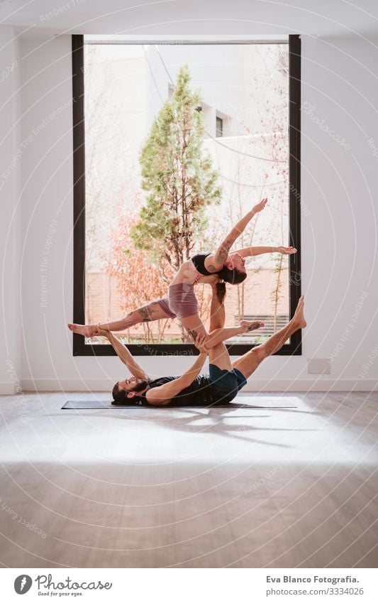 junges Paar, das Akro-Yoga am Fenster im Studio oder im Fitnessstudio praktiziert. Gesunder Lebensstil Sport Sporthalle im Innenbereich Gesundheit Mann Kraft
