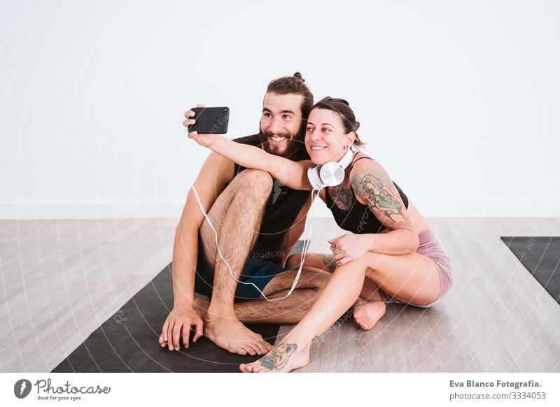 zwei Freunde im Fitnessstudio, die mit Handy und Headset einen Selfie machen und Spaß haben. Sport- und Technologiekonzept Paar Freundschaft Jugendliche Mann