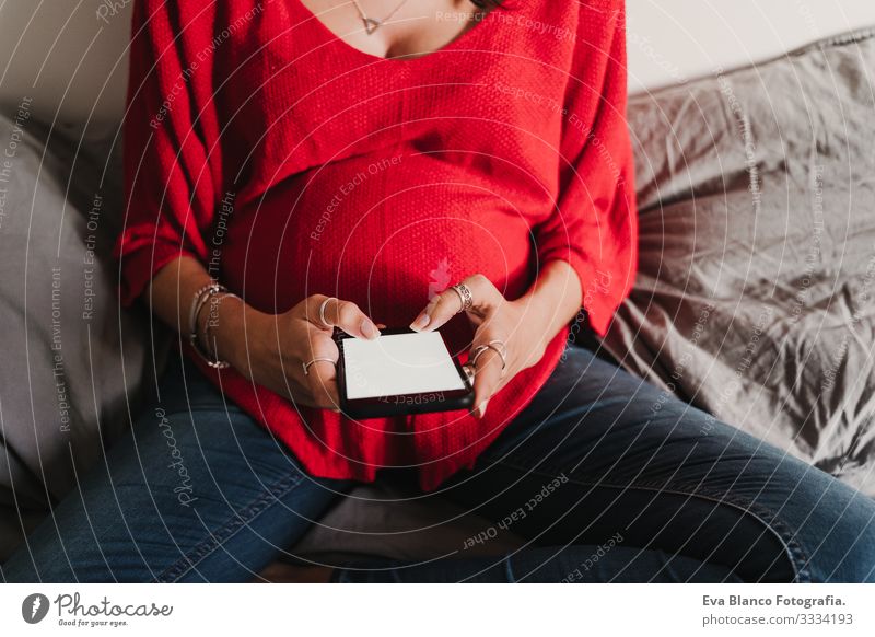 junge schwangere Frau zu Hause, die ein Mobiltelefon benutzt Handy Technik & Technologie benutzend heimwärts Bett PDA erwartend Baby bauchfrei Internet WiFi