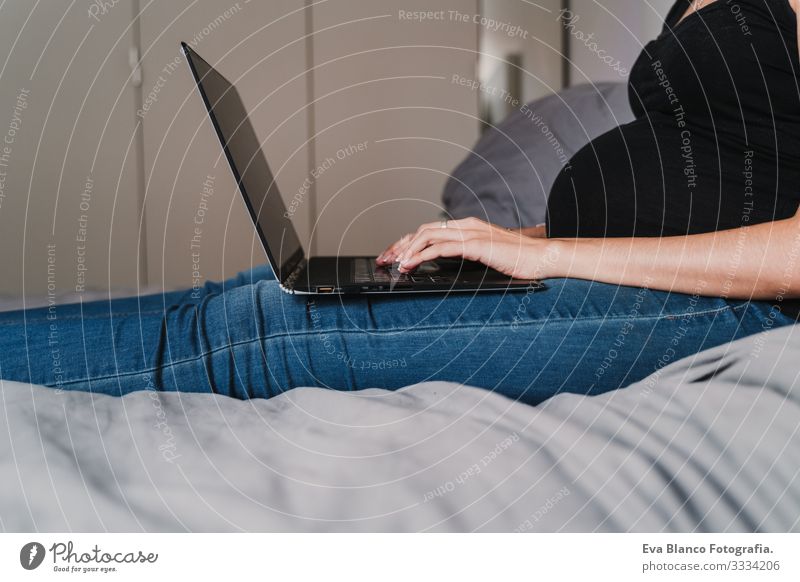 junge schwangere Frau, die zu Hause am Laptop arbeitet Notebook Computer Technik & Technologie benutzend heimwärts Bett erwartend Baby bauchfrei Internet WiFi