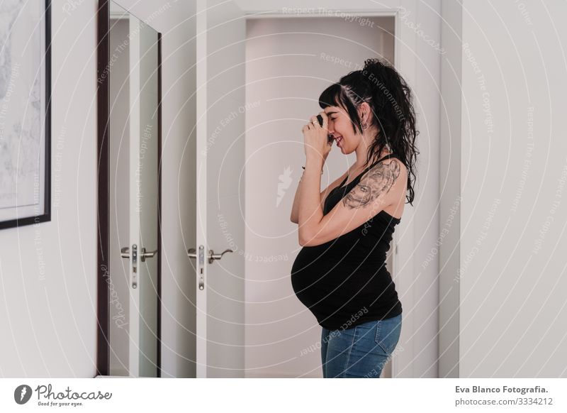 junge schwangere Frau zu Hause, die mit der Kamera einen Selfie auf dem Spiegel macht Grafik u. Illustration Fotokamera heimwärts Lächeln Glück Porträt
