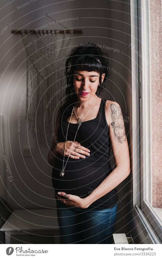 Porträt einer jungen schwangeren Frau, die zu Hause am Fenster steht heimwärts Lifestyle erwartend Tag Leben Erwartung Beautyfotografie Kindererziehung