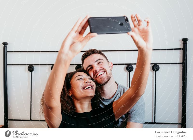 Glückliches, verliebtes Paar zu Hause. Afroamerikanische Frau und kaukasischer Mann nehmen einen Selfie mit dem Handy. ethnisches Liebeskonzept Afroamerikaner