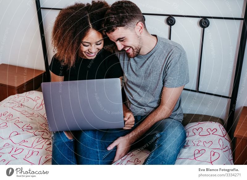 glückliches, verliebtes Paar zu Hause. Afroamerikanische Frau und kaukasischer Mann mit Laptop. ethnisches Liebeskonzept Notebook Technik & Technologie