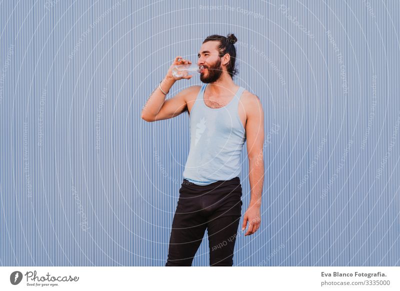 mann in der stadt, der yoga-sport betreibt und wasser trinkt. blauer hintergrund. gesunde lebensweise Yoga Mann Sport Gesundheit Außenaufnahme Großstadt
