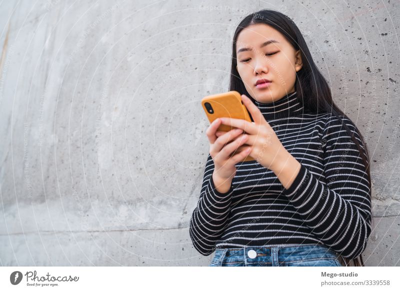 Asiatische Frau, die ihr Mobiltelefon benutzt. Lifestyle schön lesen sprechen Telefon PDA Technik & Technologie Mensch feminin Mädchen Erwachsene 1 18-30 Jahre