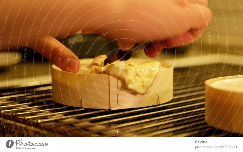 Ofenkäse wird mit einem Messer geteilt Käse lecker ungesund Rost Ofenrost Gitter Hand Abendbrot Abendessen Snack Mahlzeit Innenaufnahme Hunger Appetit