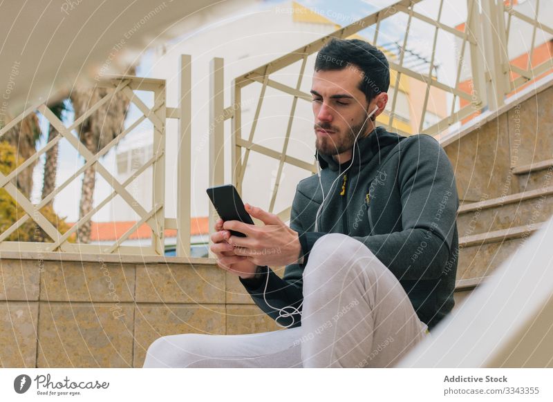 Nachdenklicher Läufer nutzt Telefon und macht Pause Mann Browsen benutzend besinnlich ernst Training Erholung Treppe aktiv männlich Smartphone nachdenklich