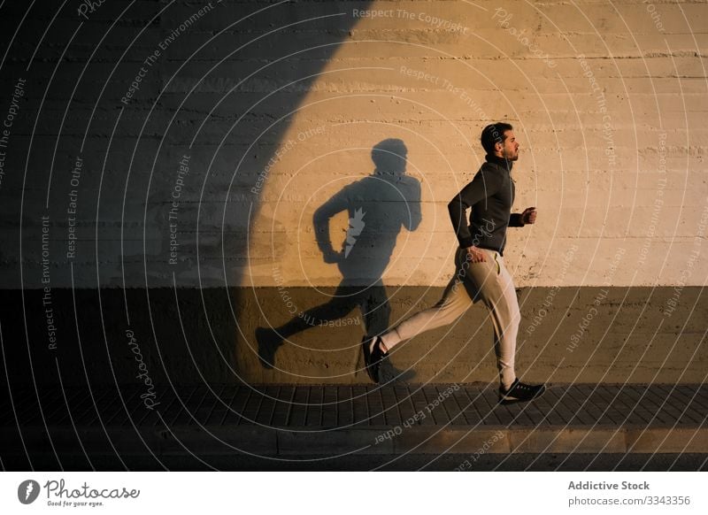 Junger Mann joggt auf der Straße in der Stadt joggen Sport Training Gesundheit aktiv Fitness urban männlich Beine Läufer Athlet Lifestyle Sportbekleidung Übung