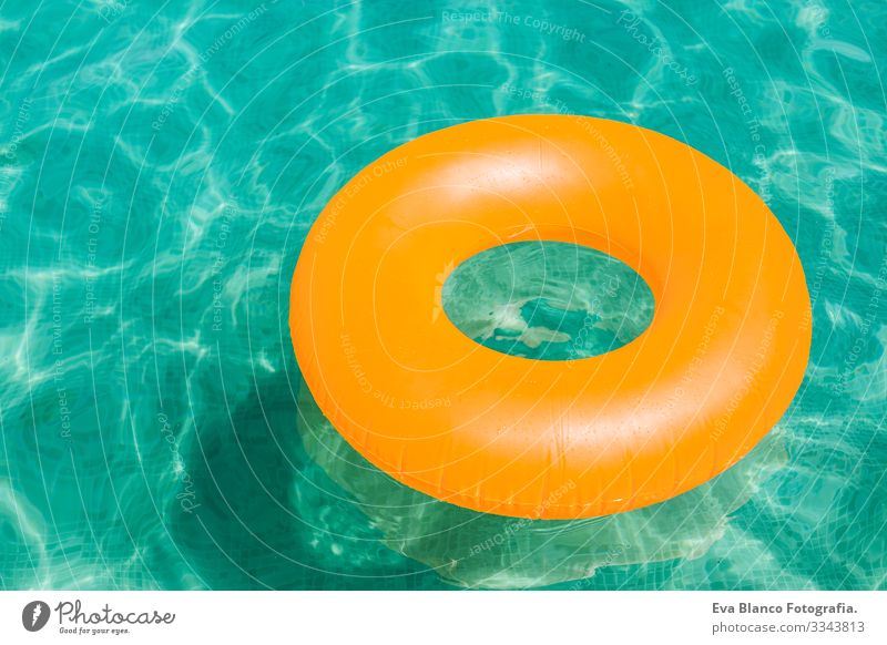 orangefarbener aufblasbarer Donut auf blauem Wasser in einem Schwimmbad. Sommer Freude Krapfen Party schön Im Wasser treiben Schwimmsport Frau Freizeit & Hobby