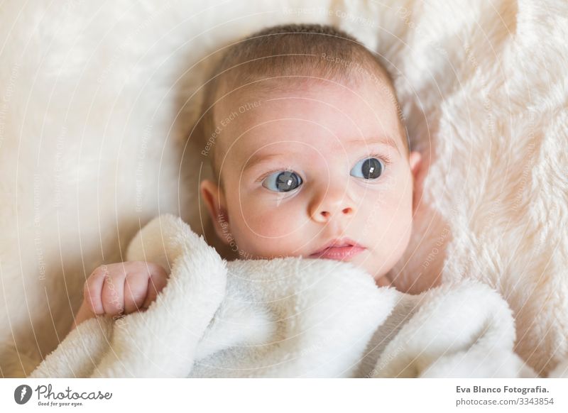 Porträt eines süßen Mädchens, das wach ist und in die Kamera schaut. Sie hält eine weiße Decke in der Hand. Weißer Hintergrund Baby niedlich klein Kind Kindheit