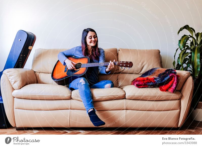 Junge schöne Frau, die auf dem Sofa stehend Gitarre spielt. Musik-Konzept Porträt Laufwerk heimwärts Inspiration Schlafzimmer Band elektrisch Felsen Ausdruck