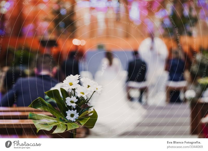Wunderschöne Blumen-Hochzeitsschmuck in einer Kirche. Selektiver Fokus. Bräutigam und Braut auf dem Hintergrund nicht erkennbar verschwommen. Heiratskonzept in der Kirche