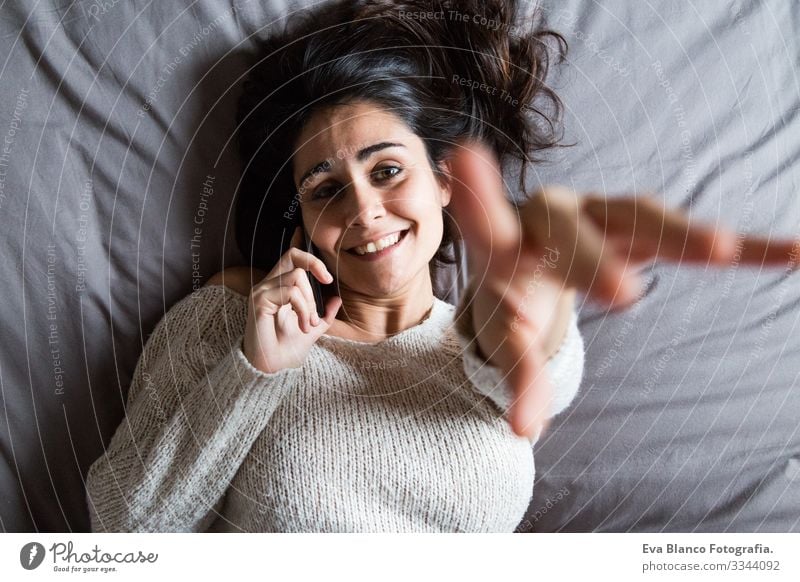 junge Frau, die am Telefon spricht und lächelt Jugendliche Kaffee Lifestyle lässig Internet Business Vernetzung Selfie sozial Bett Haus heimwärts Schlafzimmer
