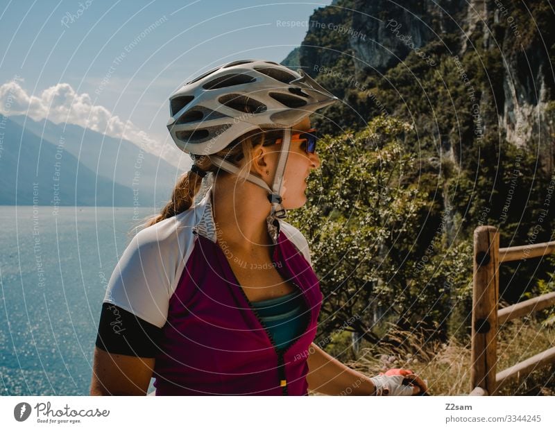 Mountainbikerin am Gardasee alpenüberquerung gardasee mountainbike mtb transalp panorama sportler sportlich zopf blond helm sicherheit schutz aussicht klippen