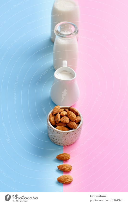 Vegane Mandelmilch auf rosa und blauem Hintergrund Gemüse Ernährung Frühstück Vegetarische Ernährung Diät Getränk Flasche frisch natürlich melken alternativ