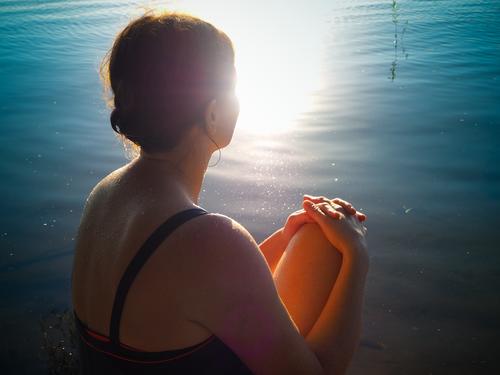 15 Minuten täglich Sonnenbad Sommer See Badeanzug brünett Zopf sitzen Wärme Geborgenheit achtsam erleben Gelassenheit Pause Sinnesorgane Sonnenlicht Oberkörper