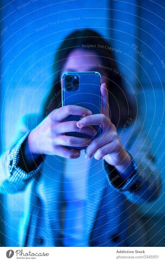 Zeitgenössische gesichtslose Dame, die mit einem Smartphone fotografiert Frau Schießen Hände benutzend Mobile Telefon Gerät Apparatur neonfarbig Licht lässig