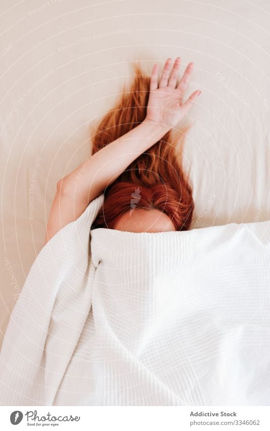 Fauler Morgen einer anonymen verschlafenen Frau Lügen Bett versteckend Arme Hand Decke Deckung unten sich[Akk] entspannen ruhen Rotschopf Lifestyle Dame