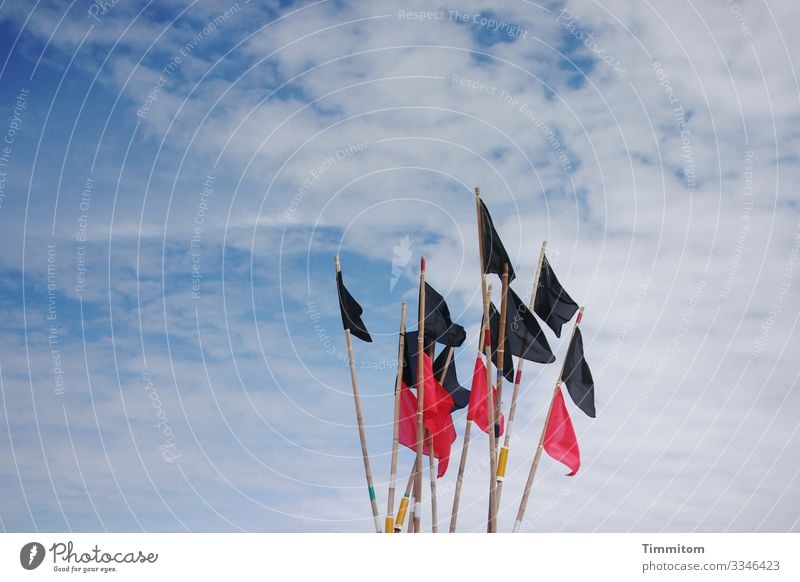 Schwarze und rote Flaggen eines Fischerbootes vor bewölktem Himmel Fahne schwarz Wolken Pole blau weiß Nordsee