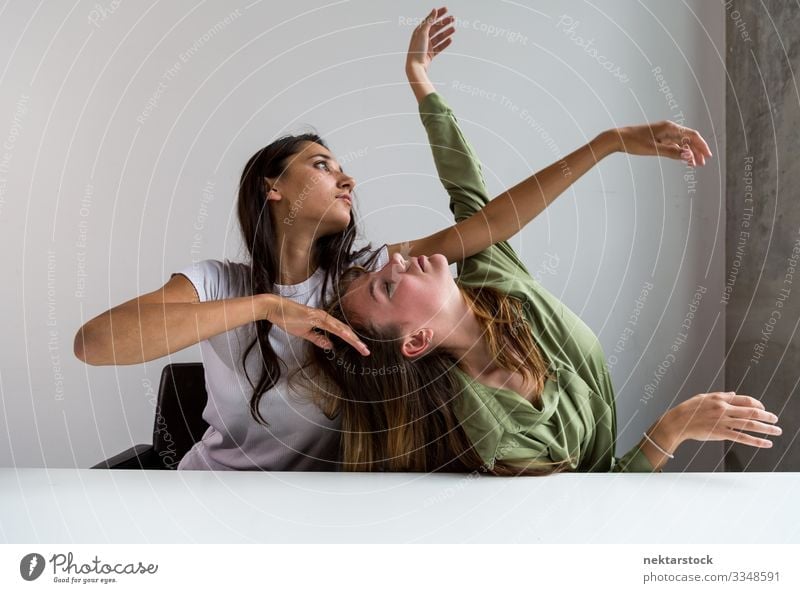 Zwei Frauen posieren künstlerisch im Büro 6 Schreibtisch Tanzen Erwachsene Freundschaft Jugendliche Jugendkultur sitzen Entwurf Arme hochgezogen