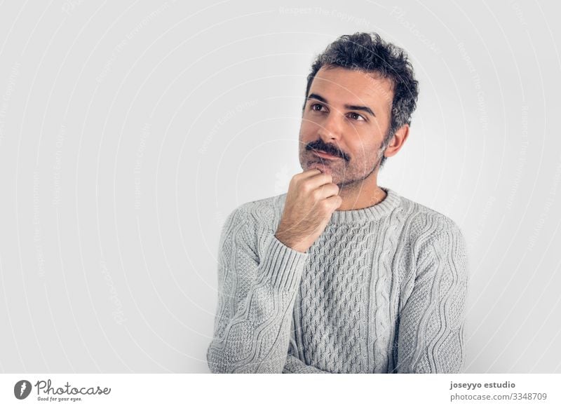Porträt eines gut aussehenden, braun denkenden Mannes mit Schnurrbart und grauem Pullover. Grauer Hintergrund. Platz zum Kopieren Erwachsener Waffen attraktiv
