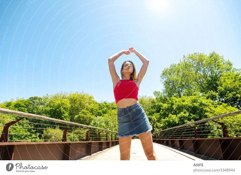 Junge Frau genießt die Sonne und die Natur Lifestyle Freude Glück schön Erholung Freizeit & Hobby Sommer Erwachsene Jugendliche Arme Wind Baum Park Brücke Rock