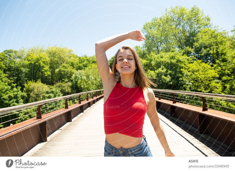 Glückliche und schöne junge Frau genießt die Sonne in einem Park Lifestyle Freude Erholung Freizeit & Hobby Sommer Erwachsene Jugendliche Arme Natur Wind Baum