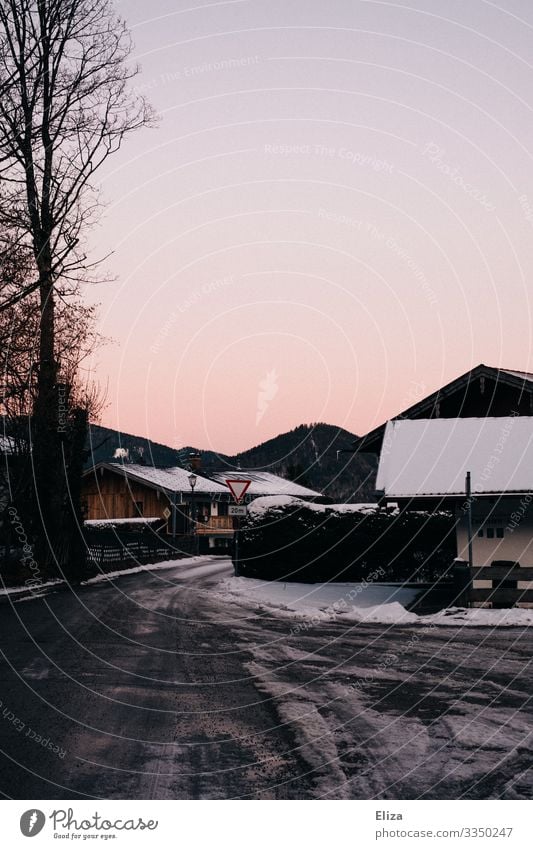 Vereiste Straße mit schneebedeckten Häusern in der Abenddämmerung im Winter Eis Schnee Abendrot Dorf Bayern Dorfstraße Landschaft Frost kalt abends Spuren