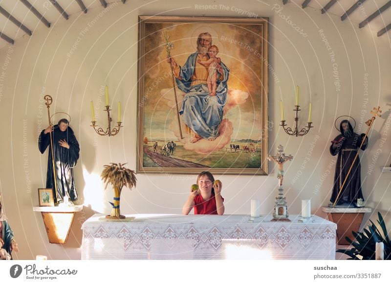 kind steht in einer kapelle hinter einem altar und spielt mit äpfeln Kind Mädchen Kirche Kapelle Altar Äpfel spielen Unfung unartig Religion & Glaube