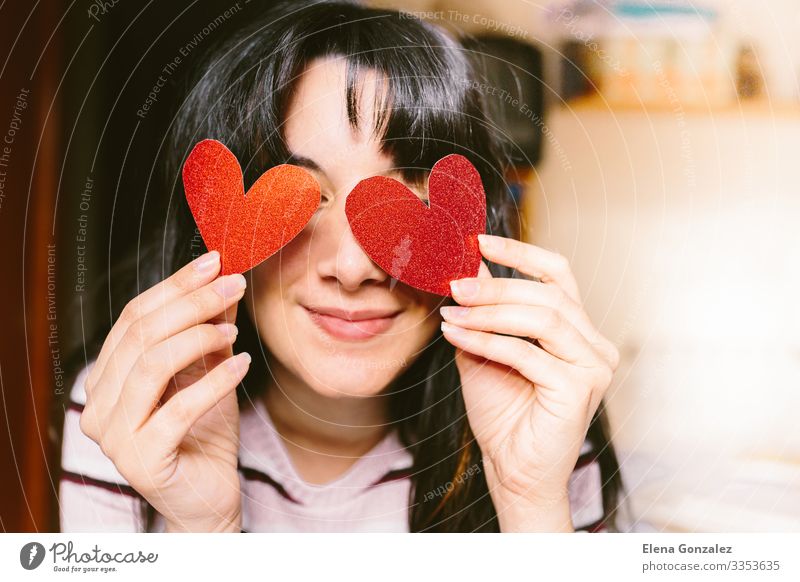 Frau mit rotem herzförmigem Karton in den Augen lächelt. Glück Flirten Valentinstag Büroarbeit feminin Erwachsene Jugendliche Lippen Herz Lächeln Liebe