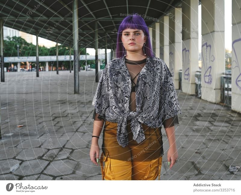 Frau mit violettem Haar schaut in die Kamera stylisch urban purpur Frisur Konstruktion glänzend Struktur Revier selbstbewusst Mode jung Stil Model Straße
