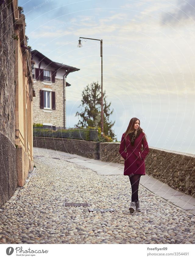 Junge Frau, die an einer Fußgängerstraße in Italien vorbeikommt laufen Straße rot Mantel jung blond Himmel wandern Tourismus Europa Europäer Ausflug Feiertag
