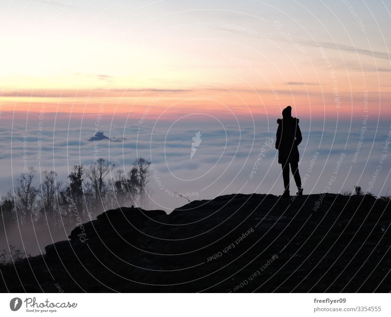 Einsame Wanderin, die vom Gipfel eines Berges aus die Wolken betrachtet einsam allein Frau Wanderer Beanie Hut oben wandern Tourist Tourismus Landschaft Höhe