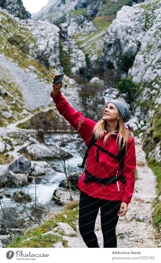 Frau mit Rucksack nimmt sich auf dem Smartphone auf dem Hintergrund der Berge mit Tourist Selfie Berge u. Gebirge benutzend reisen Natur Gerät Apparatur
