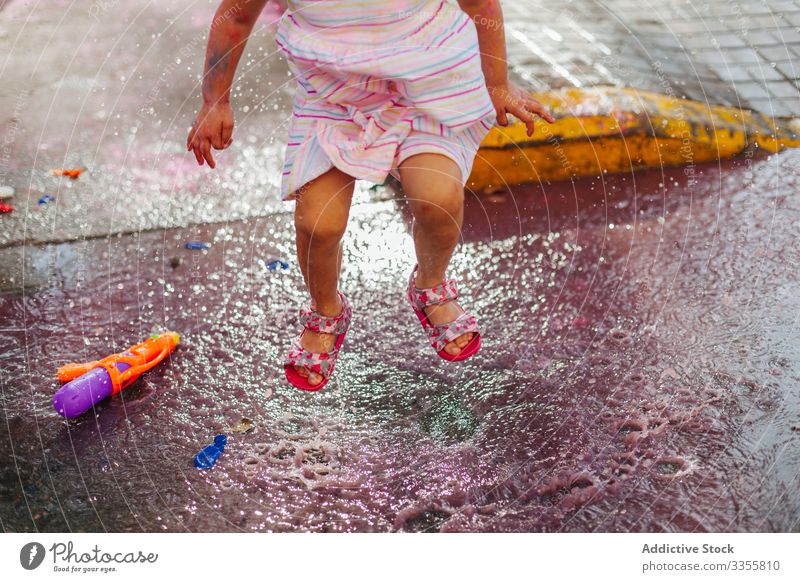 Kropfmädchen springt in bunte Wasserpfütze Mädchen Stadtfest Farbe springen Pfütze dreckig wenig Straße Sommer Wochenende Kind unordentlich Feiertag Großstadt