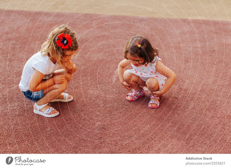 Kleine Mädchen untersuchen Gummiboden Freund Spielplatz Zusammensein spielen Wochenende Spaß ruhen Kind sitzen Lenden Freundschaft Kindheit sich[Akk] entspannen