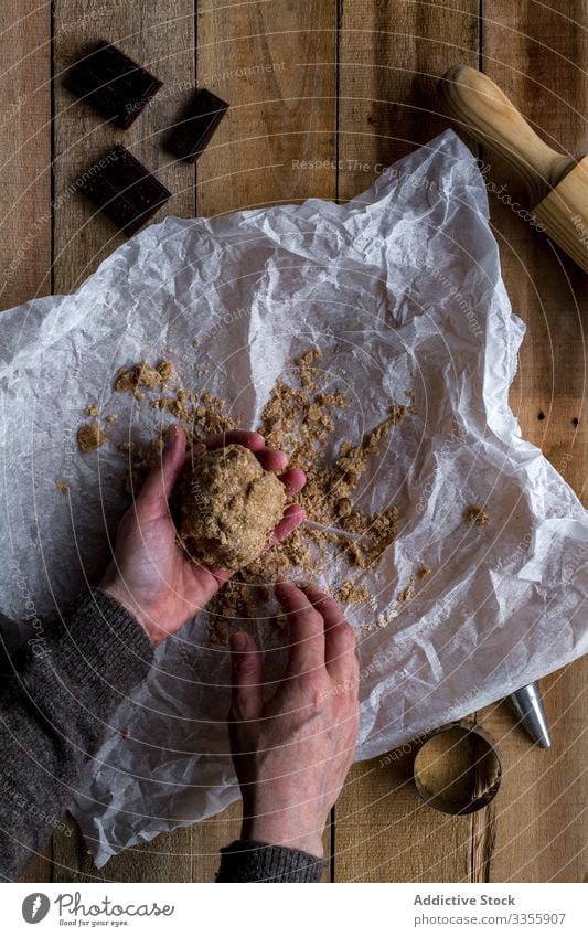 Koch hält Schokoladenteig in der Hand auf Backpapier Teigwaren Mehl Nudelholz Kochform Metall Bäckerei Lebensmittel selbstgemacht Essen zubereiten Vorbereitung